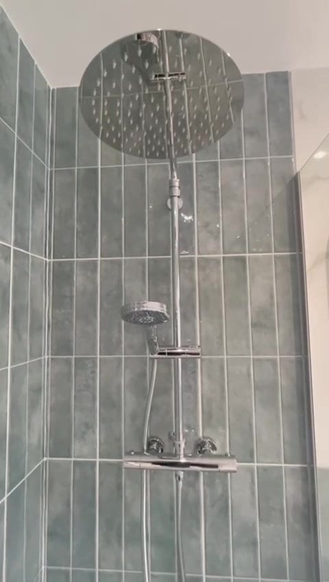Walk-in shower with rainfall shower head, exposed thermostatic valve and sage green vertical tiles